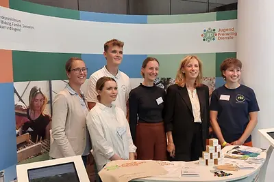 Jugendfreiwilligendienstleistende beim Tag der offenen Tür an einem Infostand.